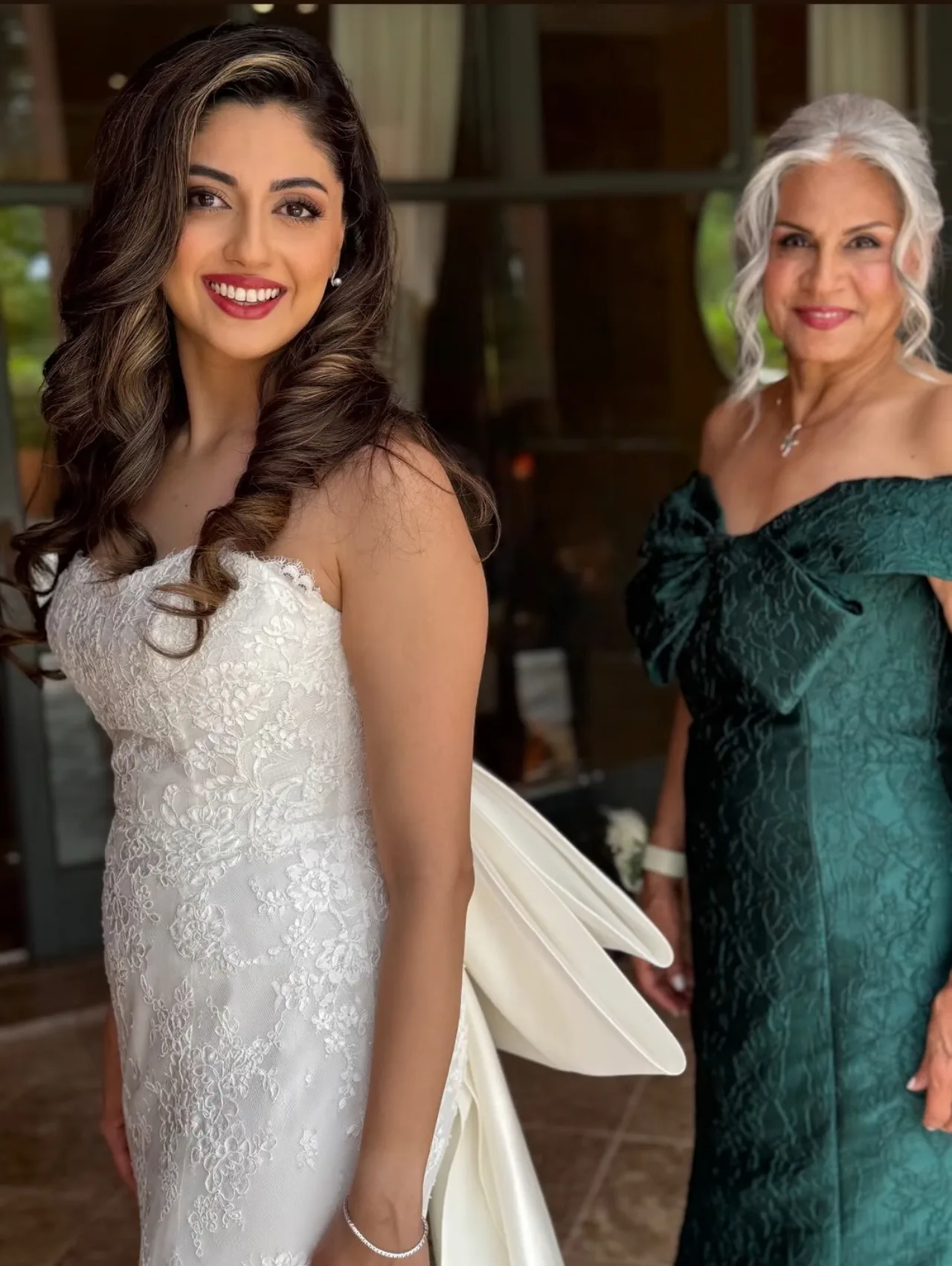 Shirin, with long waves and a lace gown, beside her mother