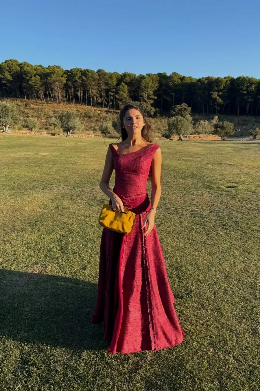 The godmother full-length at golden hour, in a garnet, almost raspberry gown by Ángel Palazuelos