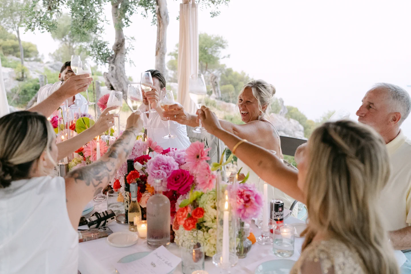 The brides and their family raise a toast on the porch at Sa Pedrissa, among colourful flowers