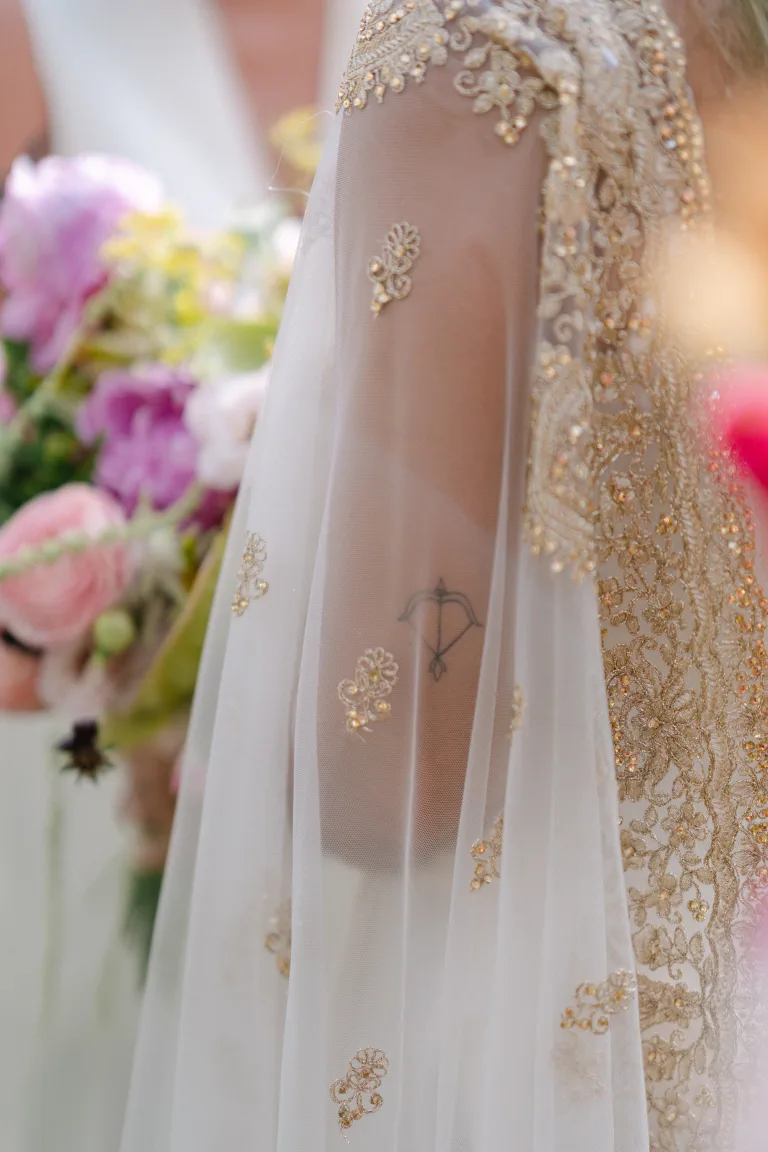 Detail of the gold embroidery on the Pakistani cape beside the colourful bouquet