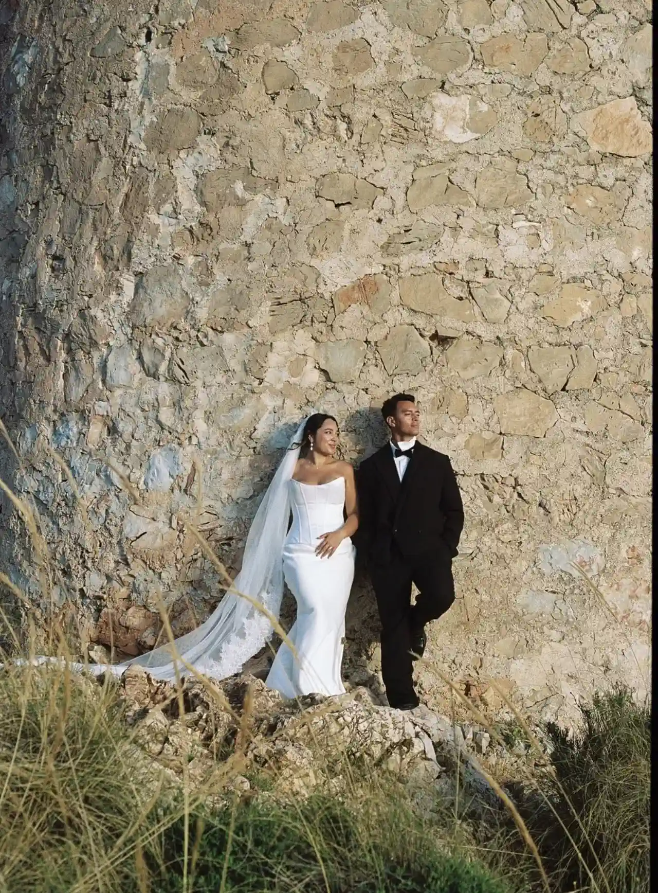 The bride, full length, with a wavy updo beside a watchtower