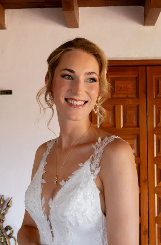 Smiling bride in a lace gown with an updo and loose strands at Fort Inglés, Mijas