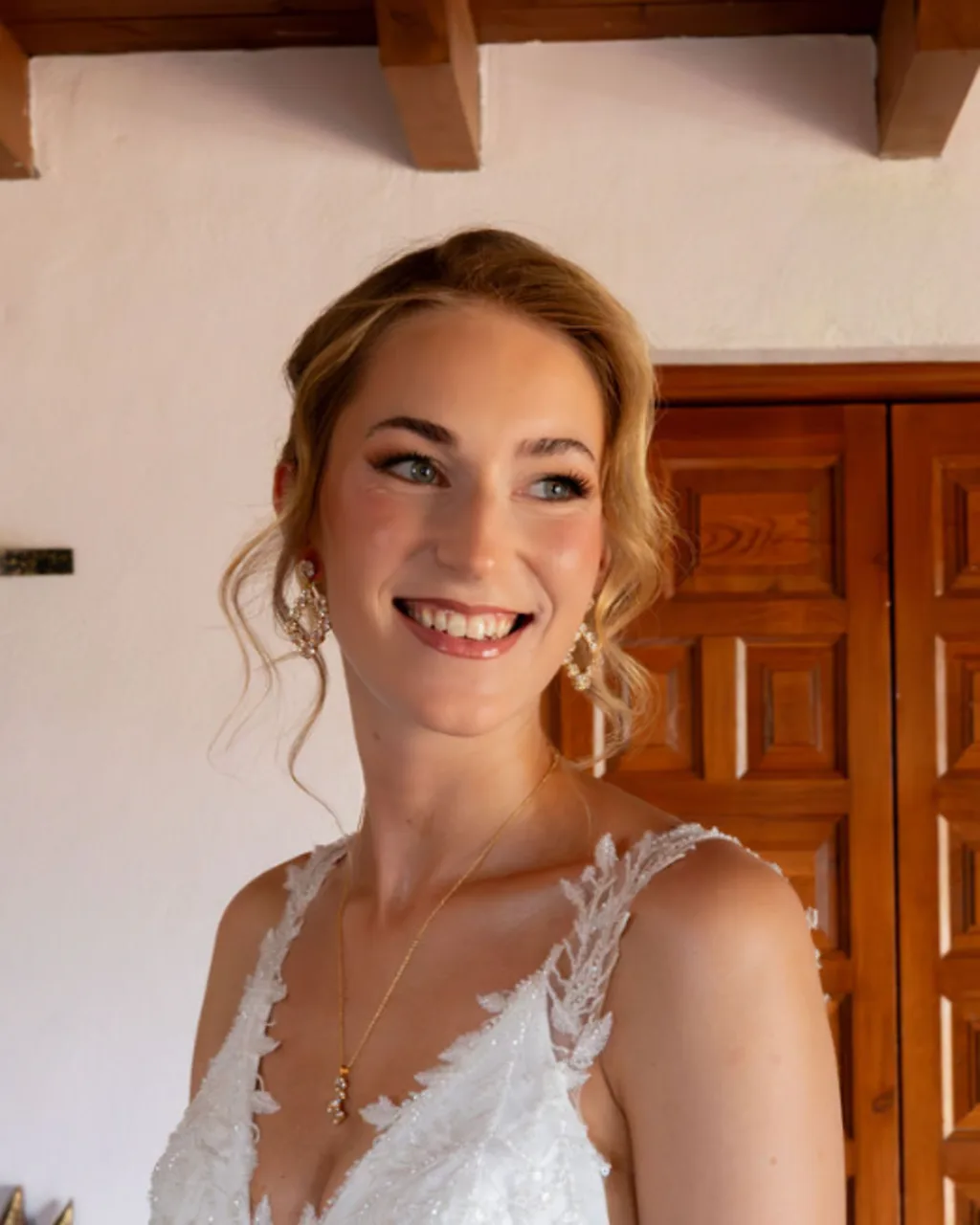 Novia sonriente con vestido de encaje y recogido con mechones sueltos en Fort Inglés, Mijas