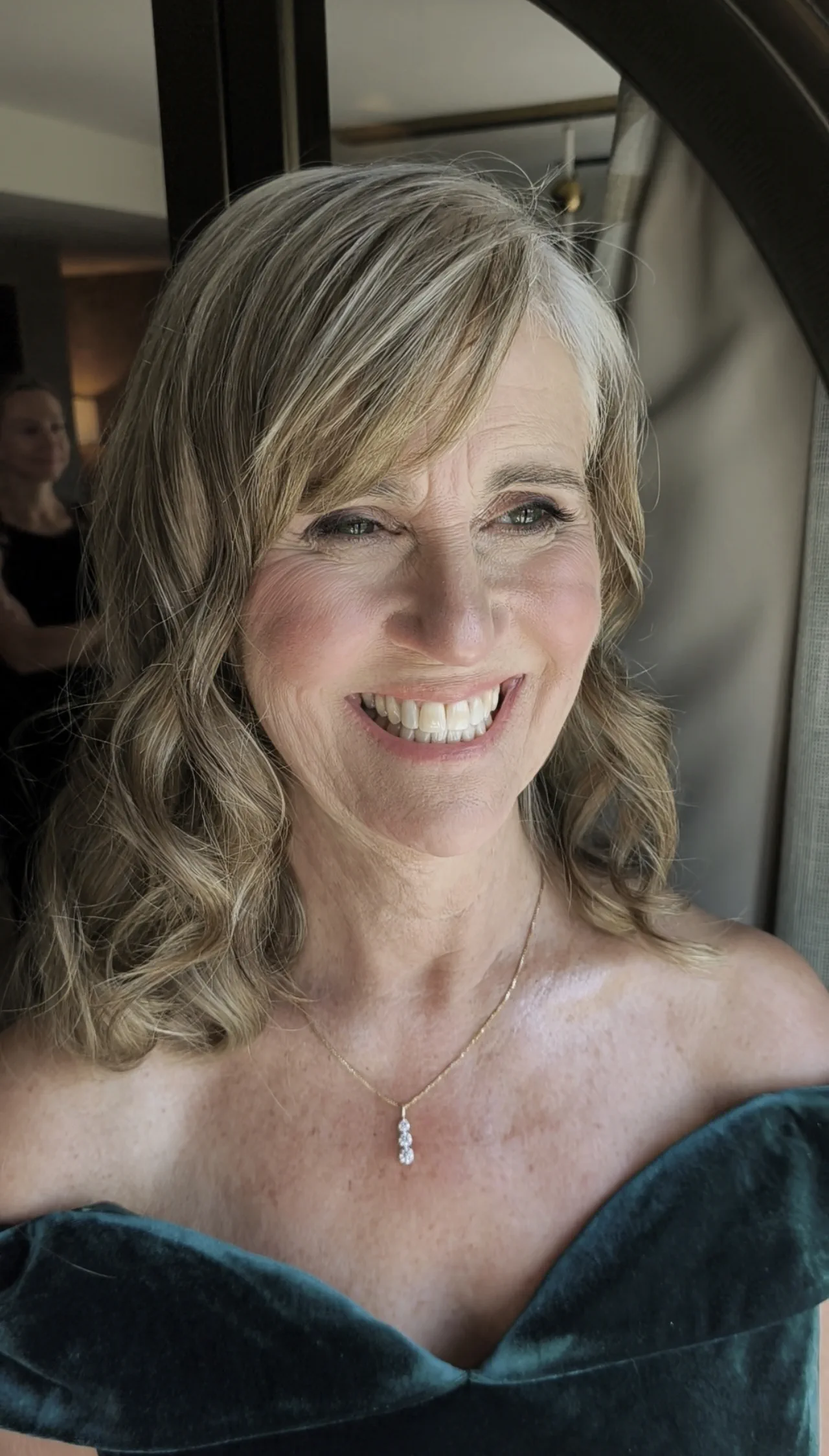 Smiling mother of the bride with soft waves, a side-swept fringe and radiant makeup for mature skin