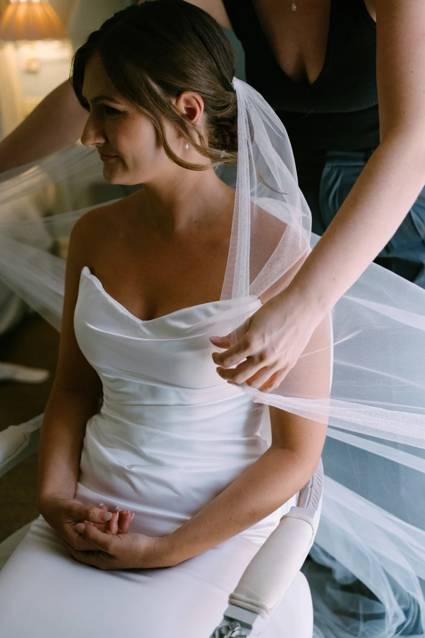 Placing the sheer tulle veil over the bride