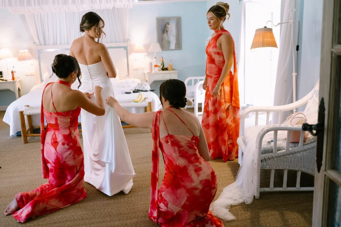 The bridesmaids help the bride with her dress in the bedroom at El Molino del Duque, Manilva