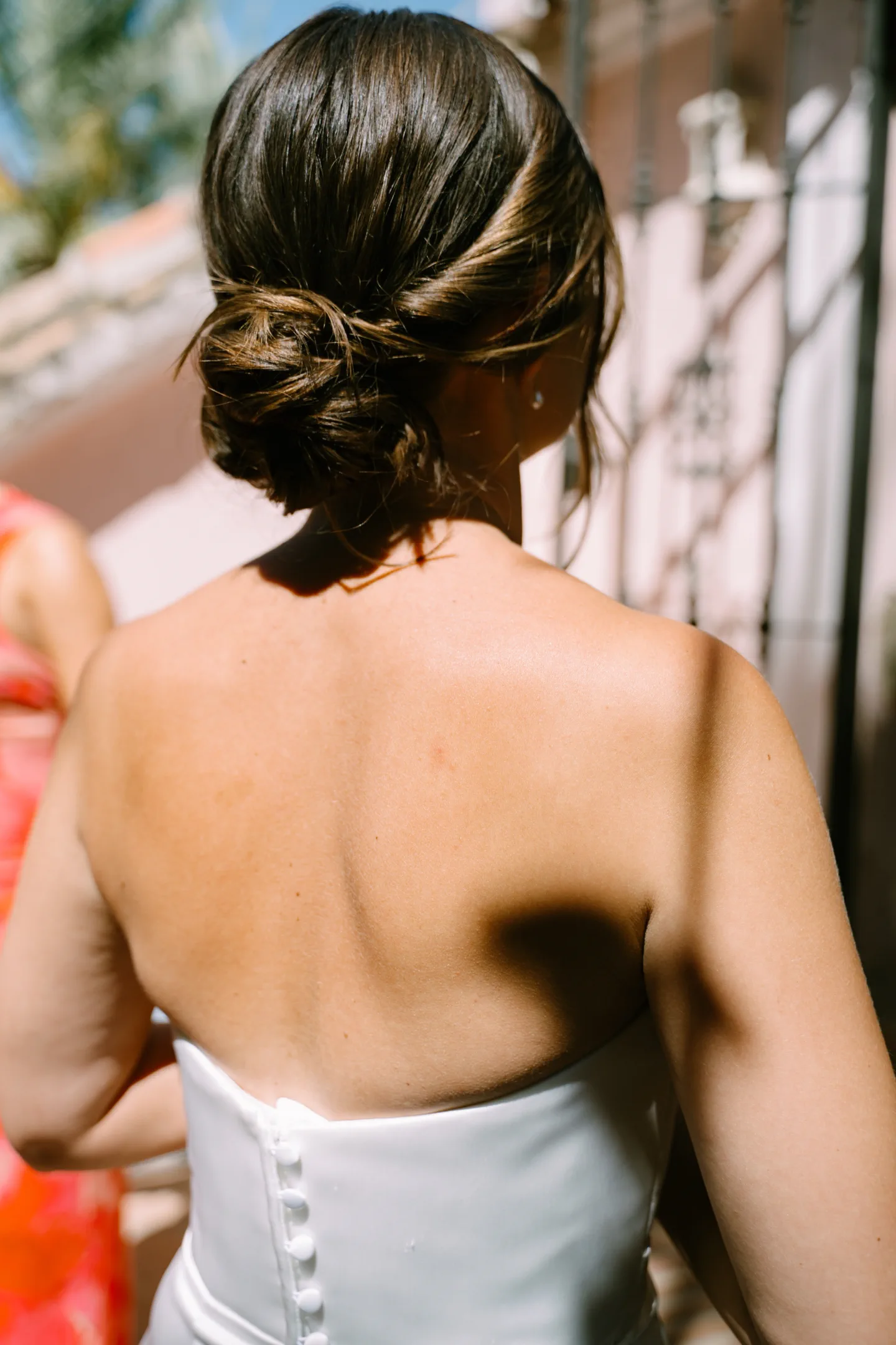 The bride from behind, her relaxed low updo with a few loose strands