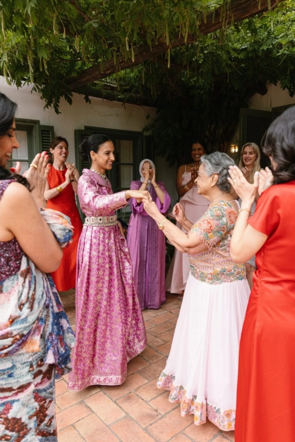 Hanadi's family dance and clap on the terrace, dressed in pink, fuchsia and red