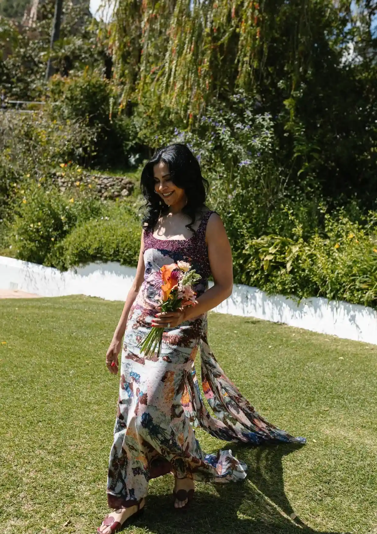 Hanadi's mother, with waves and a bouquet, walks across the lawn