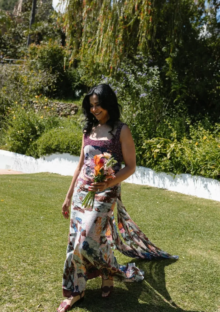 Hanadi's mother, with waves and a bouquet, walks across the lawn