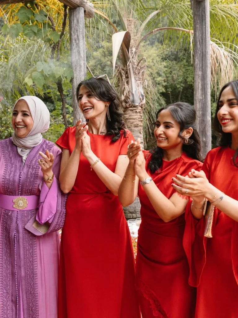 The bride's friends, with waves and red dresses, clap in the garden at Torre de Tramores, Benahavís