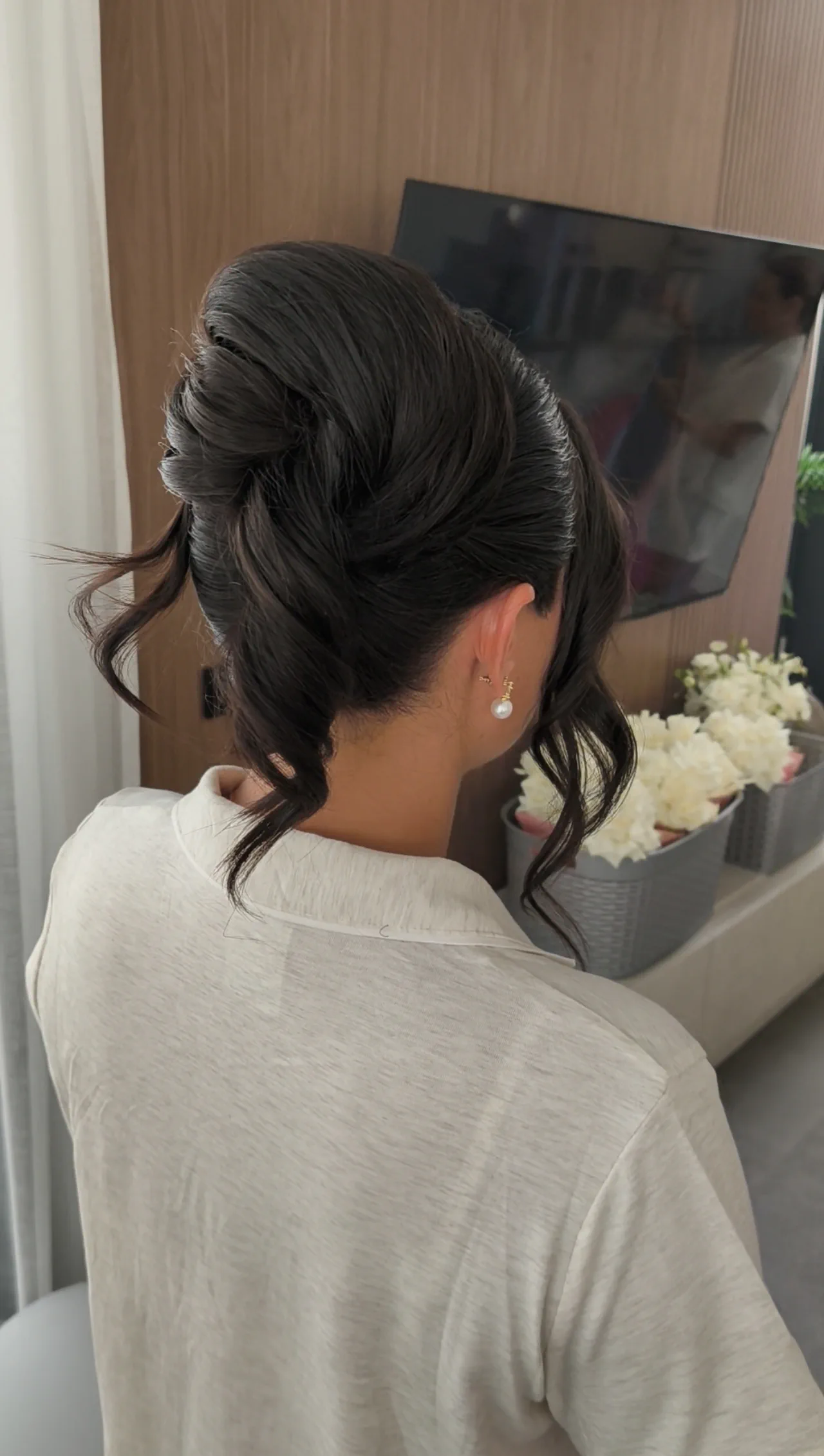 A bridesmaid seen from behind, with a sleek high updo and loose wavy strands