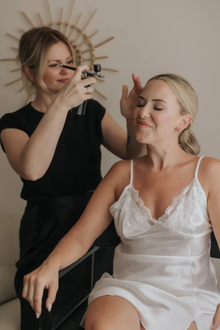 The makeup artist sets the bride's glowing makeup at the end of her wedding preparation in Mijas