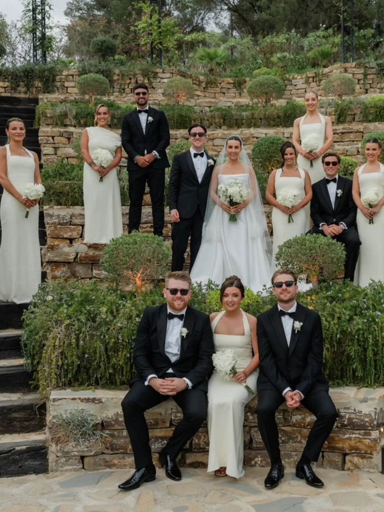 The couple with the bridesmaids and groomsmen on the stone-terraced garden