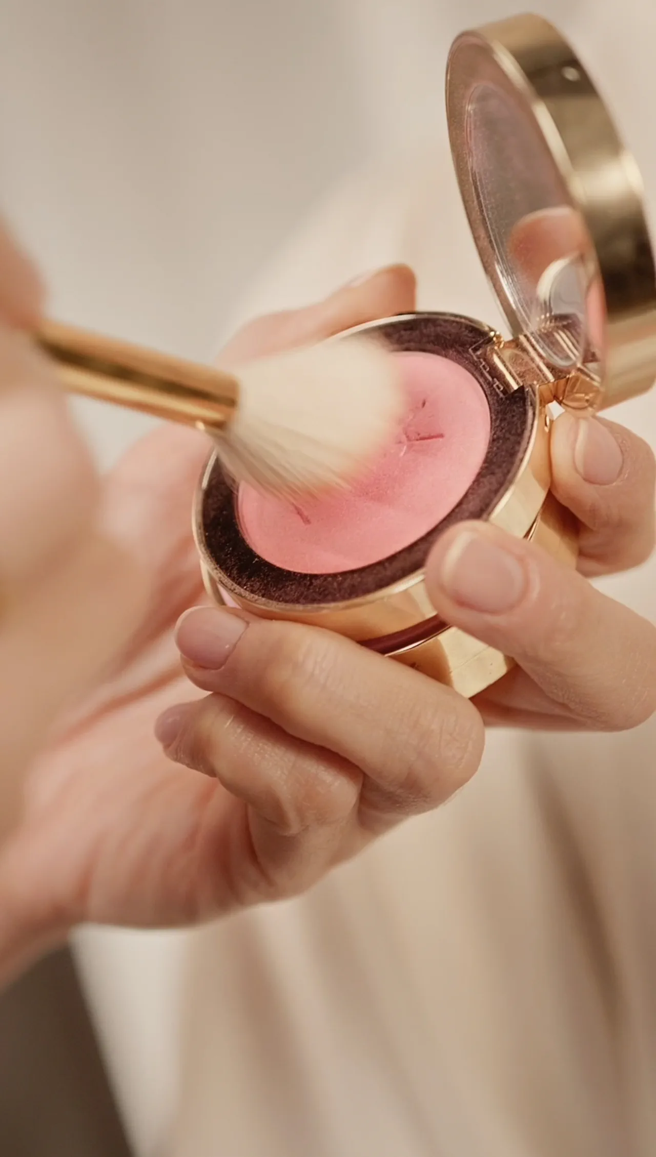A brush with pink blush over the palette