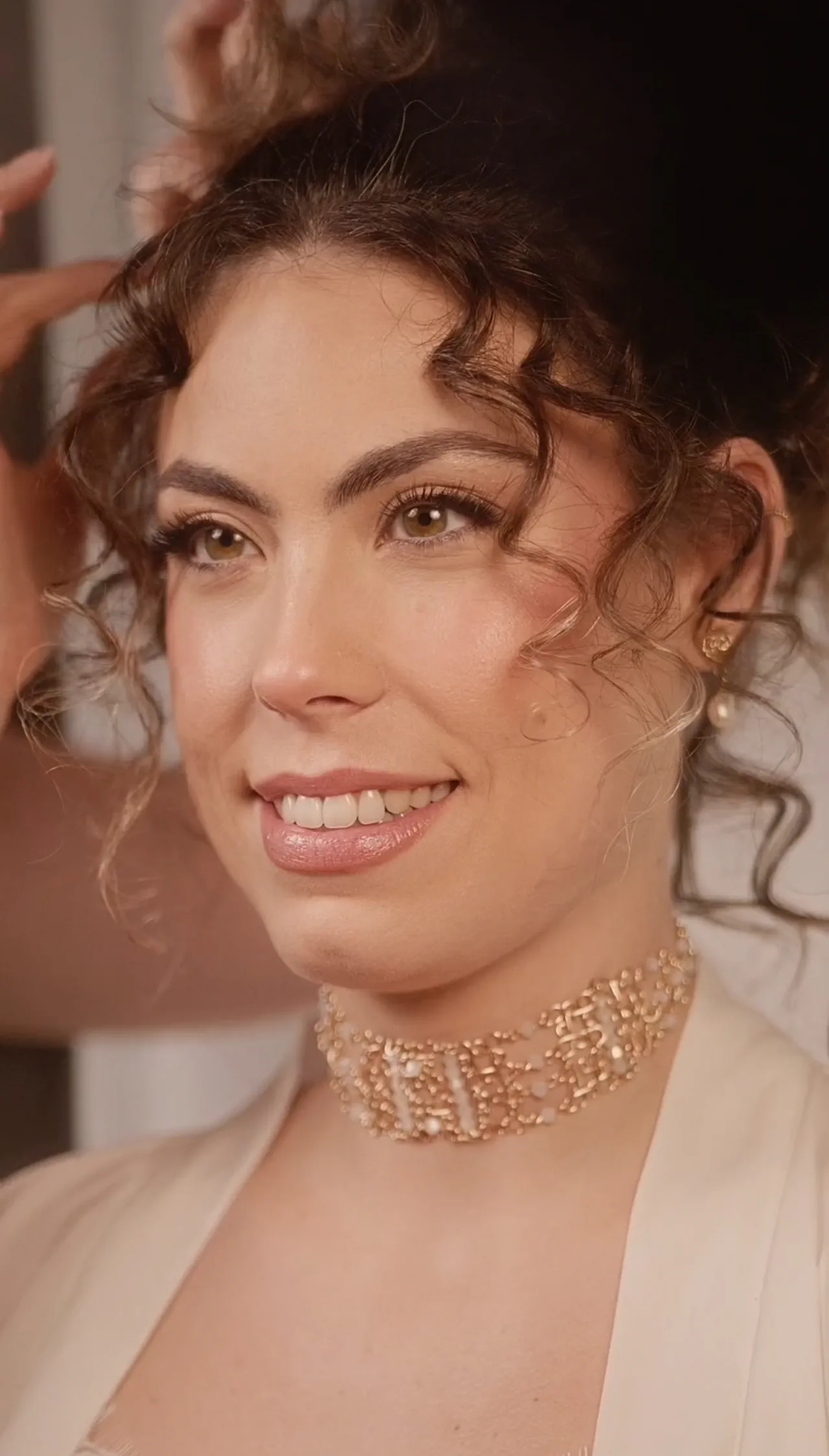 The model smiles with the finished curly updo and the Argia Tocados choker
