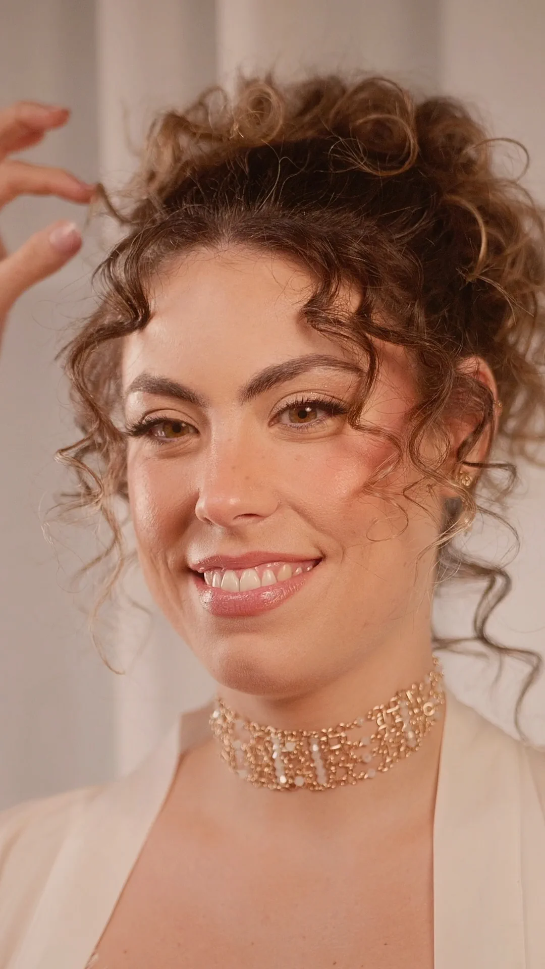 A Grecian high updo with natural curls and a gold choker