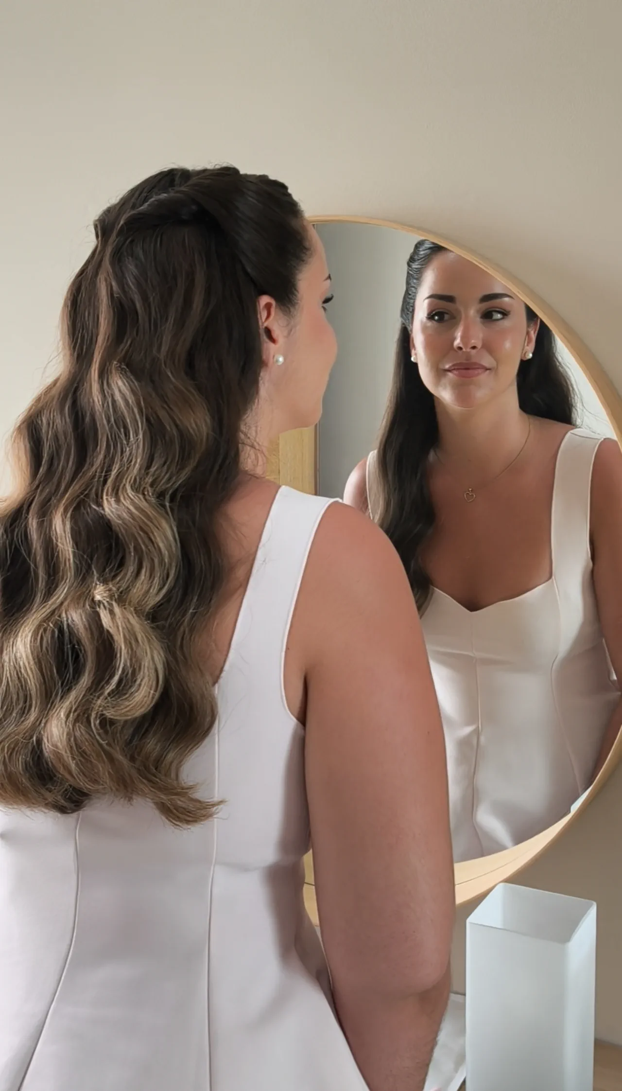 Half-up hair with long waves, seen from behind and reflected in a round mirror