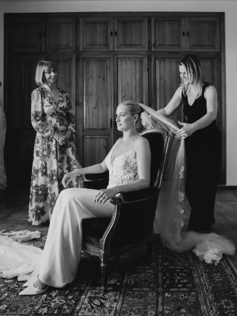 Verónica places the veil on the seated bride, with her mother beside her