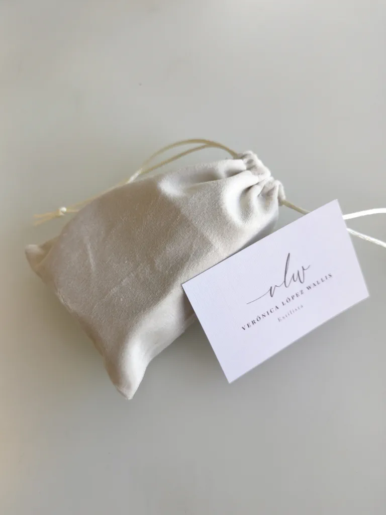 Closed cream velvet pouch with a drawstring, beside Verónica López Wallis's card