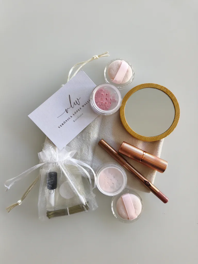Bridal makeup touch-up kit with a bamboo mirror, jars of blush and setting powder with their puffs, a Charlotte Tilbury lipstick and lip liner, and an organza pouch with the hygiene kit