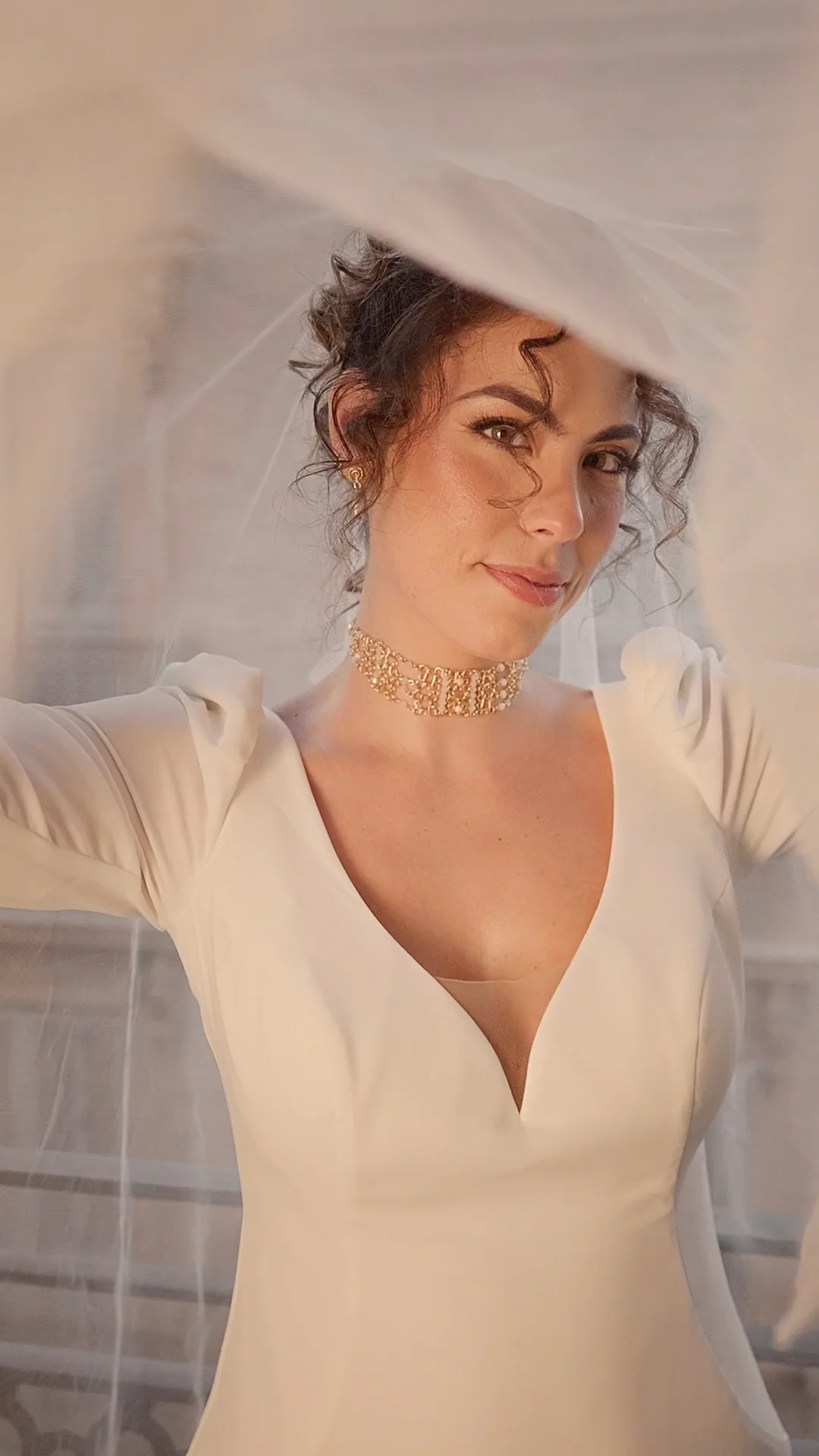 The model with a veil, a curly updo and a V-neck dress